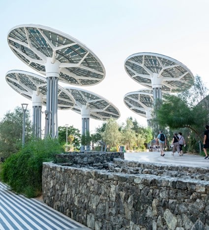 Estructuras modernas con paneles solares en forma de sombrillas, instaladas en un espacio público. Las columnas sostienen paneles cirulares que producen energía solar al tiempo que ofrecen sombra a los viantes. Esta tecnología evidencia la creciente importancia que se le da en España a la energía solar y a su rentabilidad.